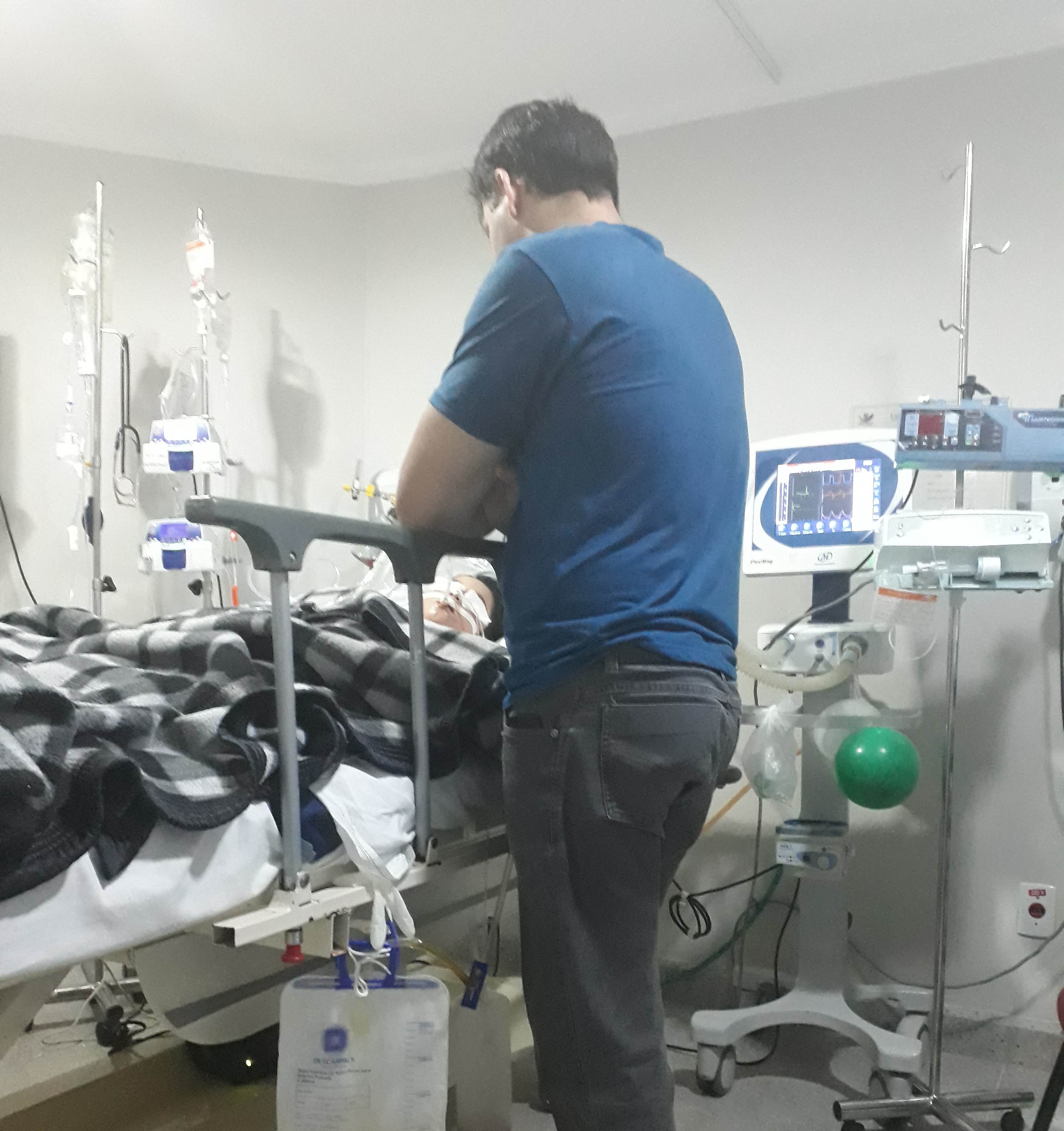 Harlem standing at Kauan's hospital bed